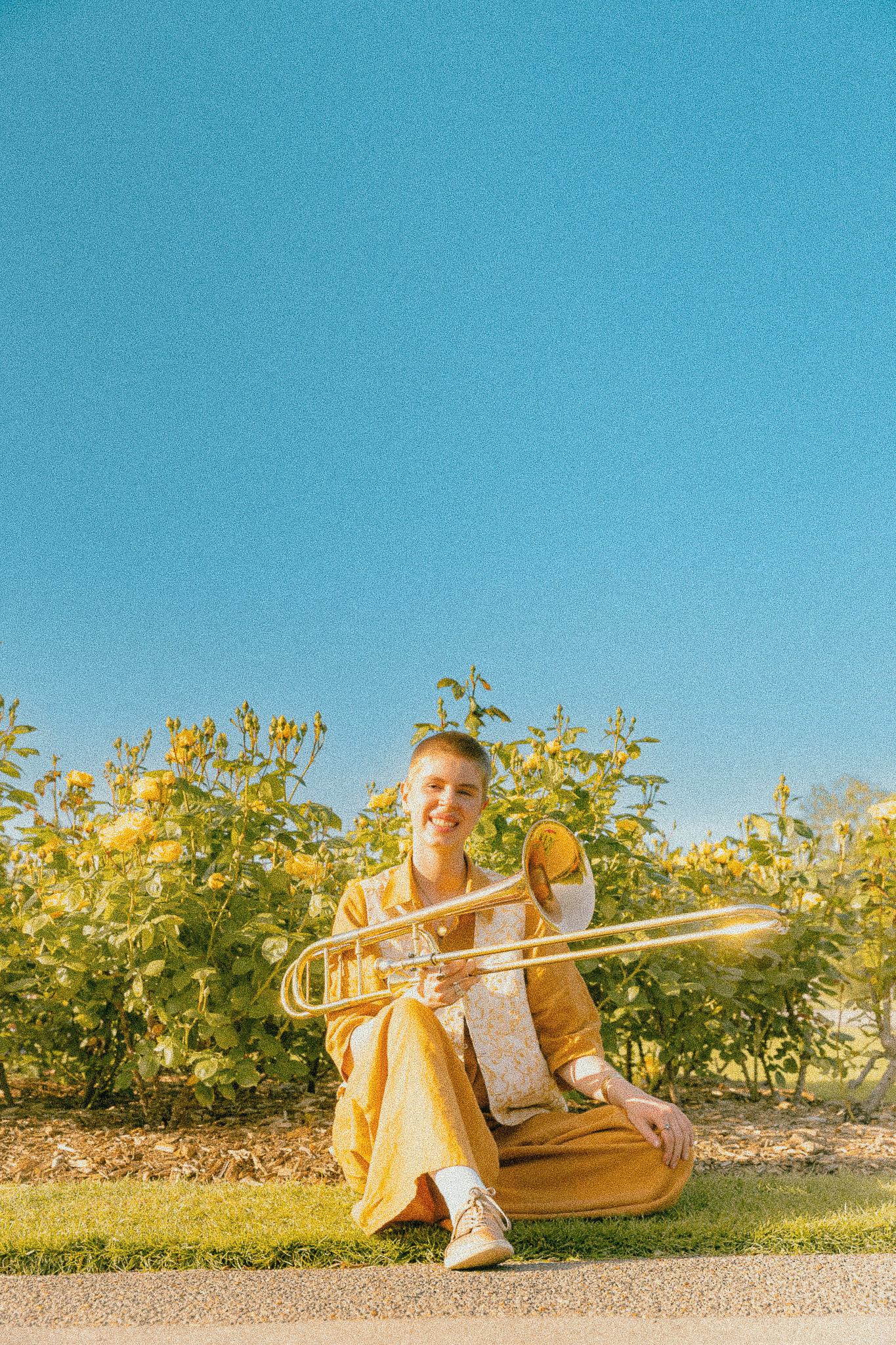Jess sitting in a garden holding a trombone
